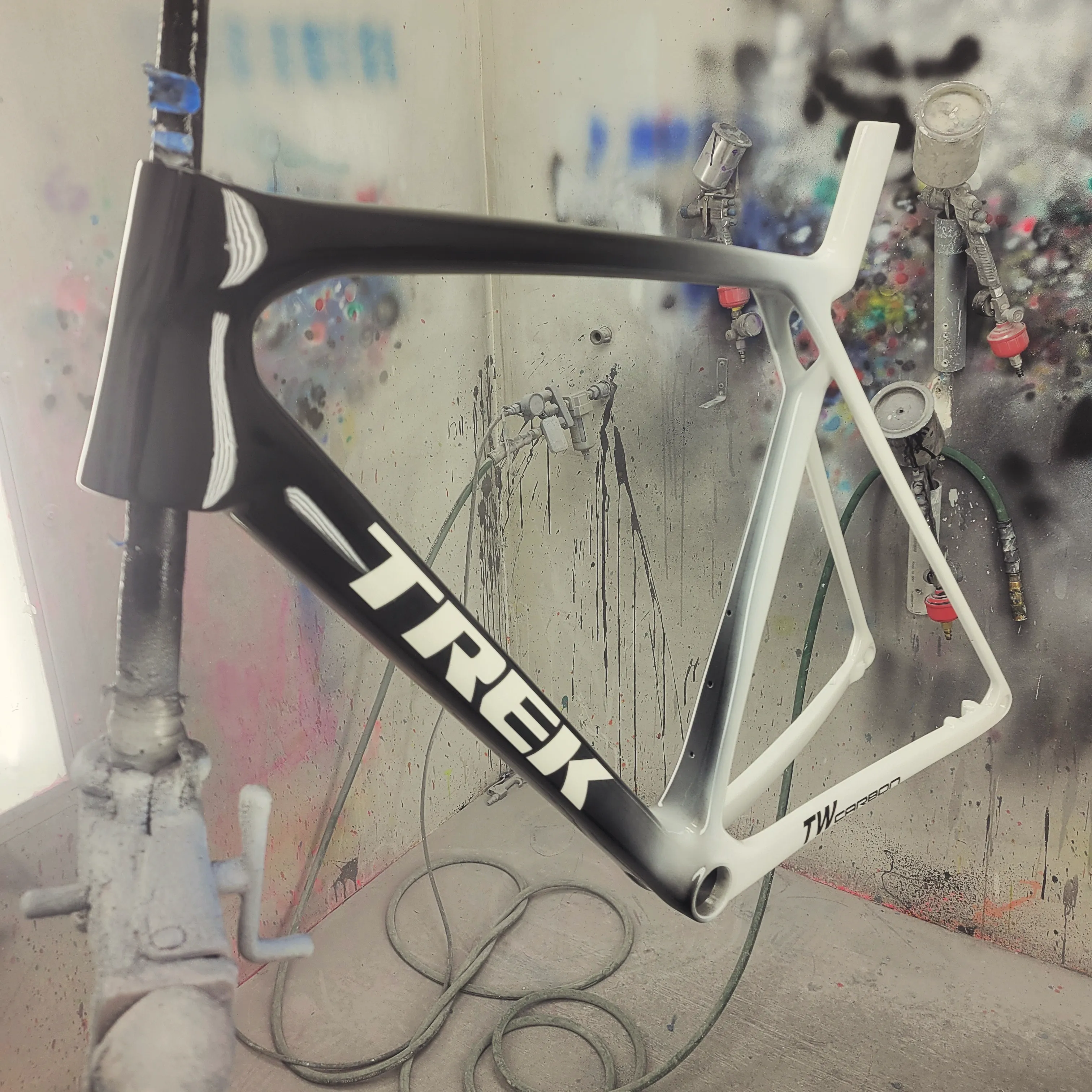 Bike paint design: black to white fade on a Trek carbon road frame, photographed in the paint booth